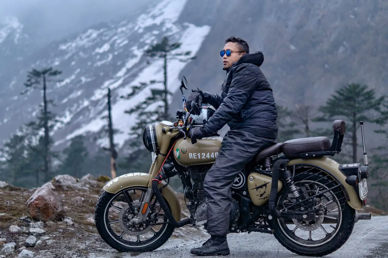 Motorcyclist enjoys a scenic winter ride in the snowy mountains, embracing the cold adventure.