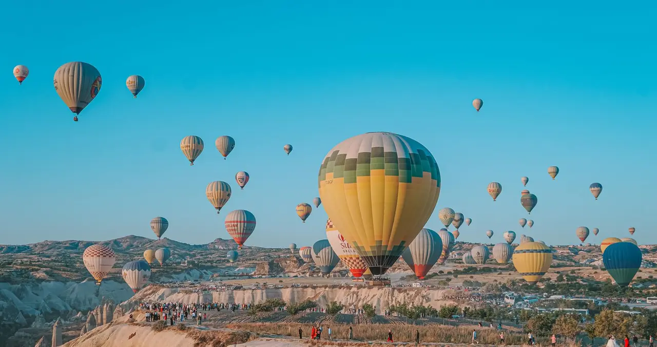 Vibrant hot air balloons soar over Cappadocia's unique landscape in Turkey.