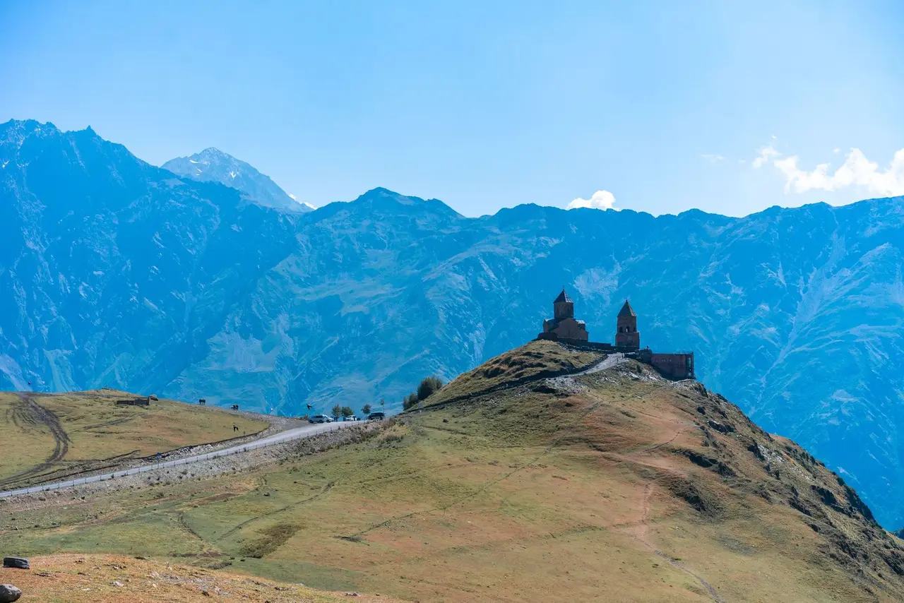 Stunning view of Gergeti Trinity Church atop a hill against majestic Georgian mountains.