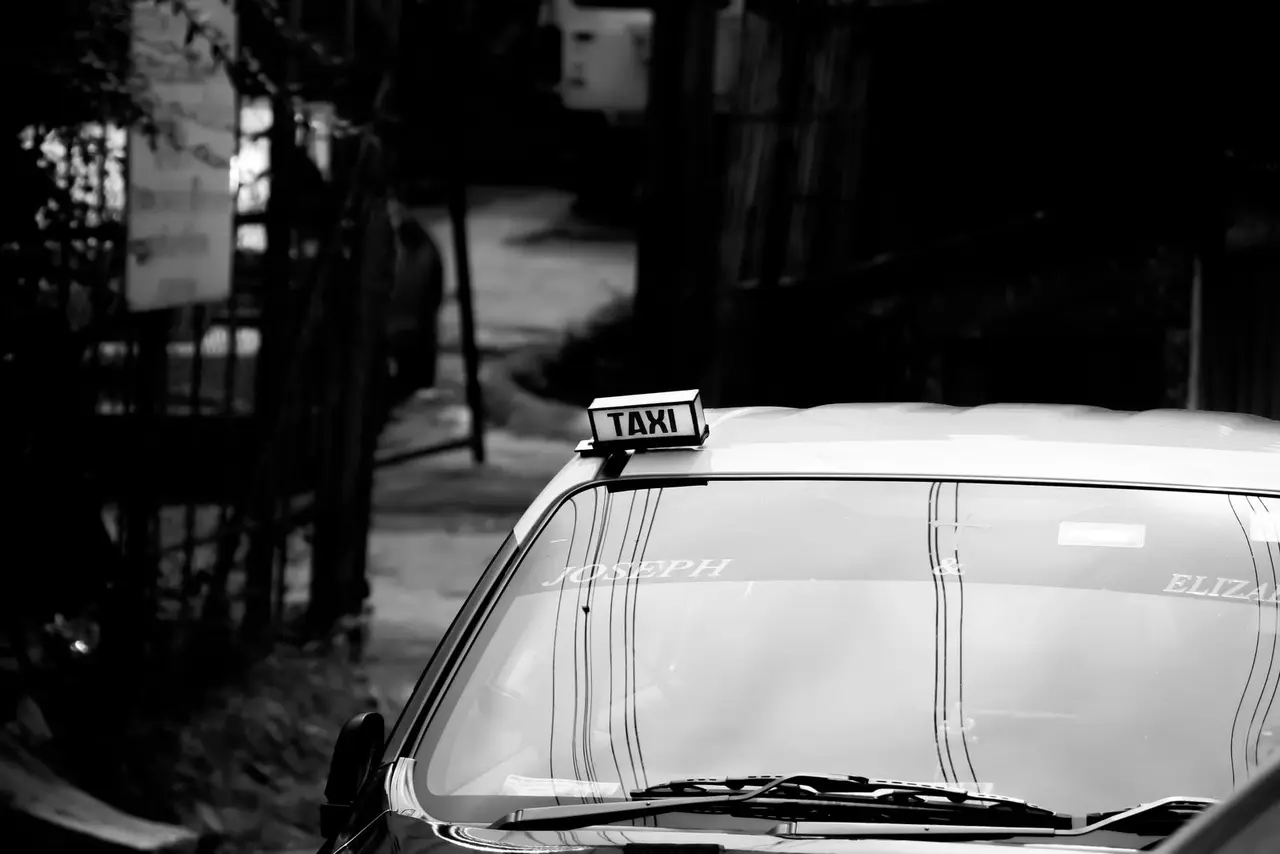 Black and white image of a taxi on a street in Shillong, India, evoking urban life.