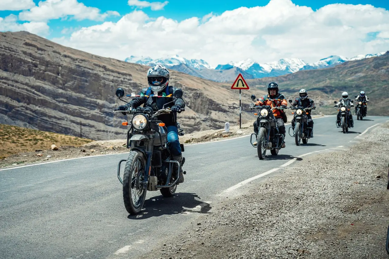 A group of motorcyclists ride through the stunning mountain landscapes of Spiti Valley, India.