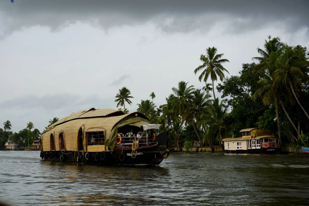 Scenic view of a traditional Kerala houseboat cruising through lush backwaters.